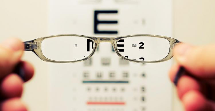 Glasses being held up infront of an eye test