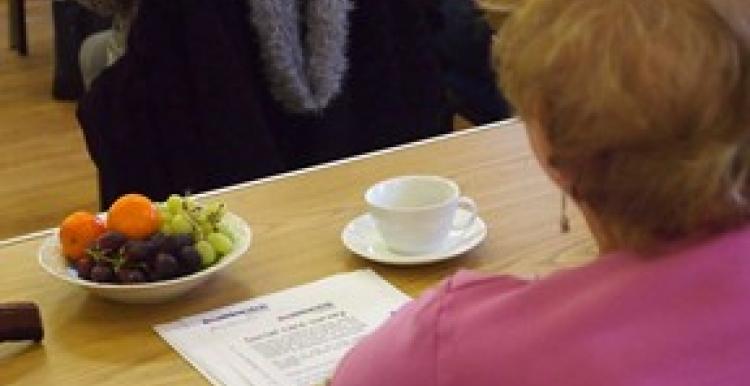Person sitting at table with a coffee and Healthwatch literature